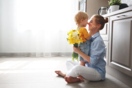 happy mother's day! baby son congratulates mother on holiday and gives flowers